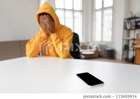 Despondent man with head in hands and phone Despondent man with head in hands and phone 113689914