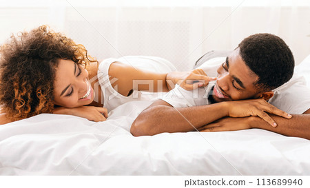 Cheerful woman touching her husband nose in bed 113689940