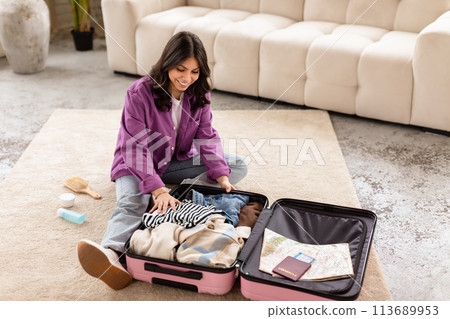 Woman packing clothes in a pink suitcase Woman packing clothes in a pink suitcase 113689953