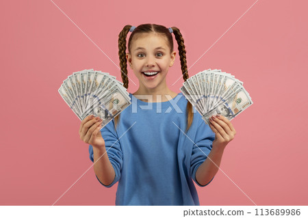 Girl holding money with excited expression on pink background Girl holding money with excited expression on pink background 113689986