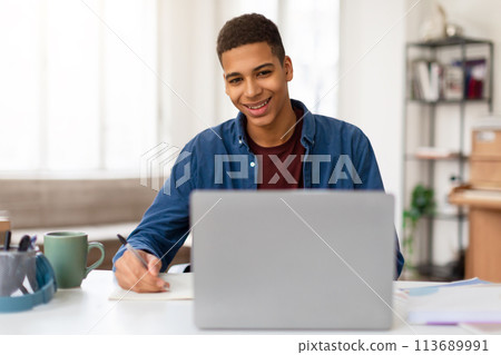Smiling man writing notes with laptop 113689991