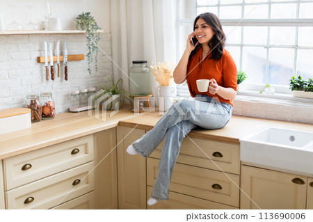 Woman talking on phone with a coffee mug 113690006
