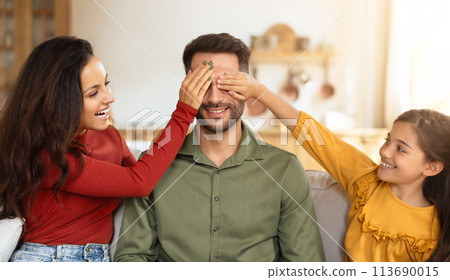 Playful eye-covering game with family at home 113690015