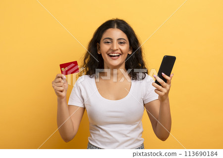 Cheerful woman holding phone and credit card 113690184