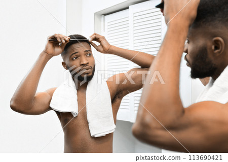 Man styling hair in front of bathroom mirror Man styling hair in front of bathroom mirror 113690421