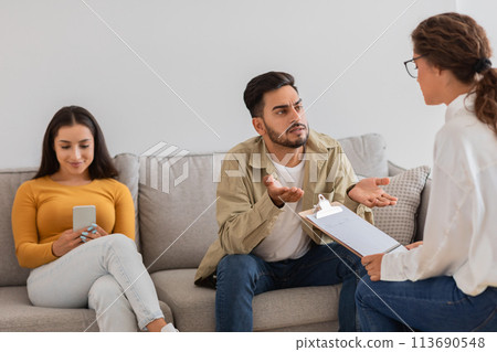 Man discussing with woman therapist holding clipboard 113690548