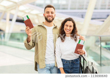 Couple smiling with travel documents at airport 113690640
