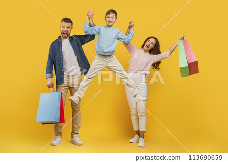 Parents and child jumping with shopping bags 113690659