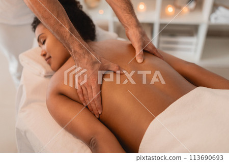 Close-up of hand massaging African American woman's back Close-up of hand massaging African American woman's back 113690693