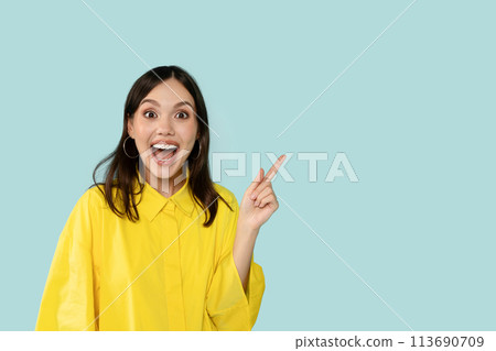 Happy Young Woman Pointing Aside At Copy Space on Blue Background Happy Young Woman Pointing Aside At Copy Space on Blue Background 113690709