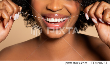 Close-up of black woman flossing, showcasing healthy teeth 113690781