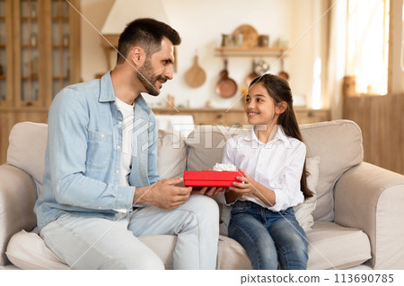 Father giving daughter a gift box at home Father giving daughter a gift box at home 113690785