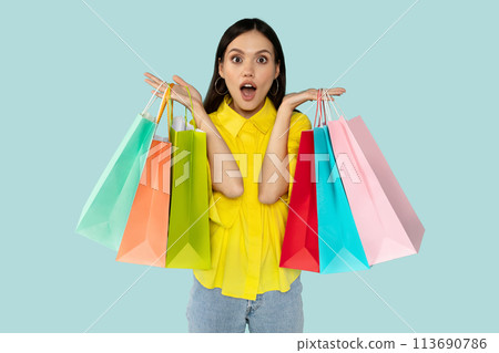 Excited surprised young woman with shopping bags at blue backgtound Excited surprised young woman with shopping bags at blue backgtound 113690786