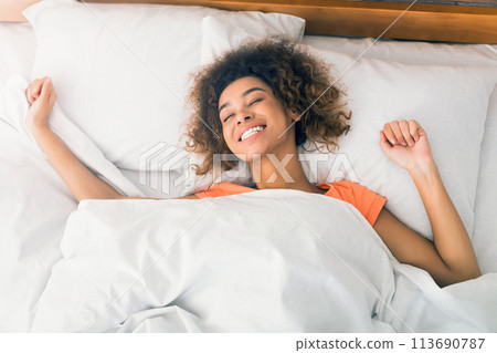 Happy girl waking up and stretching in the morning 113690787