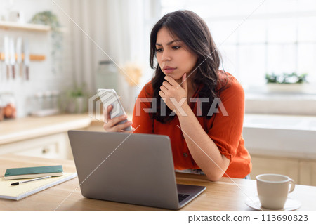 Woman looking at phone with concern at home 113690823