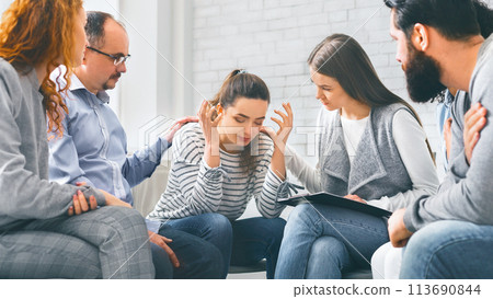 Depressed woman sharing her problems with group on therapy session 113690844