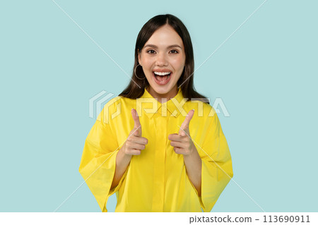 Playful happy beautiful young hispanic woman in casual yellow outwear pointing at you and smiling 113690911