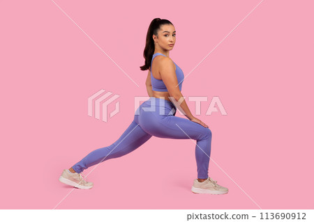 Woman in fitness clothing performing a lunge Woman in fitness clothing performing a lunge 113690912