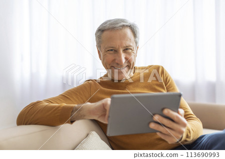 Smiling senior man with tablet on sofa 113690993