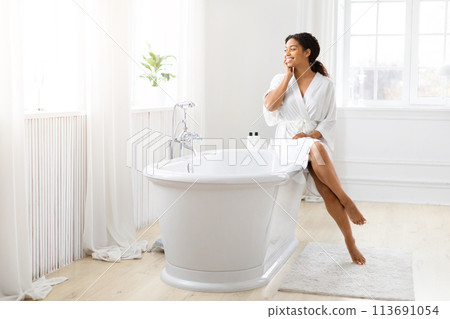 Woman touching face with foot dipped in bathtub Woman touching face with foot dipped in bathtub 113691054