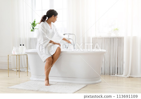 Woman preparing for a bath in bright room Woman preparing for a bath in bright room 113691109
