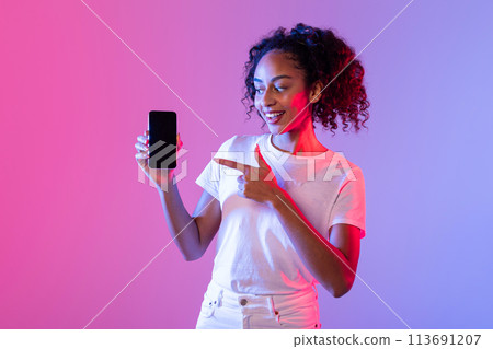 Woman indicating phone screen in purple light Woman indicating phone screen in purple light 113691207