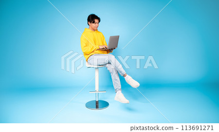 Teen using laptop on stool with focused look Teen using laptop on stool with focused look 113691271