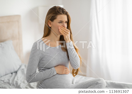 Pregnant woman feeling nauseous in bedroom Pregnant woman feeling nauseous in bedroom 113691307