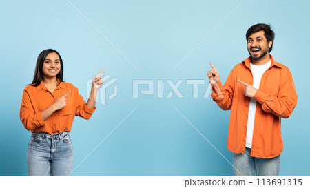 Cheerful middle eastern couple pointing aside at empty space, studio 113691315