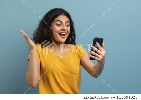 Joyous woman video calling on teal 113691325