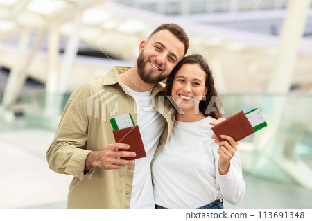 Smiling Couple Holding Passports and Boarding Passes at Airport Smiling Couple Holding Passports and Boarding Passes at Airport 113691348