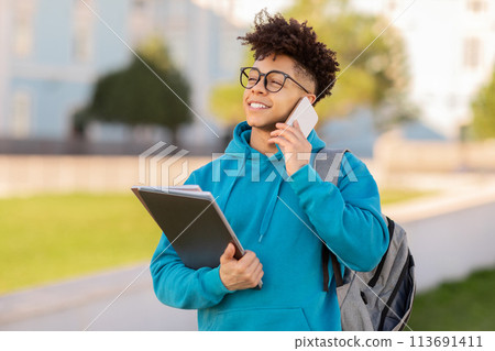 Student talking on phone with textbook in hand 113691411