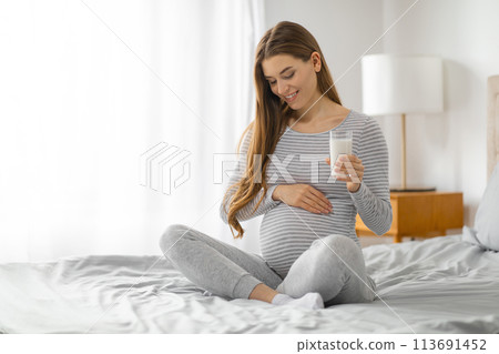 Content pregnant woman with a glass of milk Content pregnant woman with a glass of milk 113691452