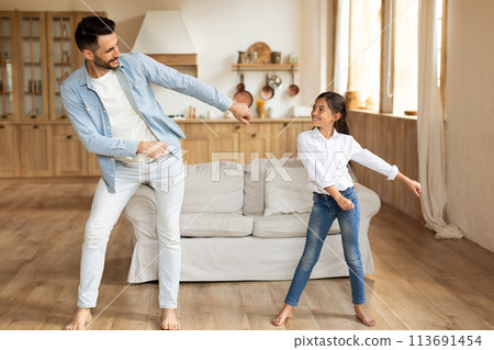 Father and daughter dancing in living room 113691454