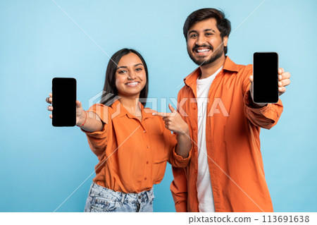 Couple showing a smartphone screen on blue Couple showing a smartphone screen on blue 113691638