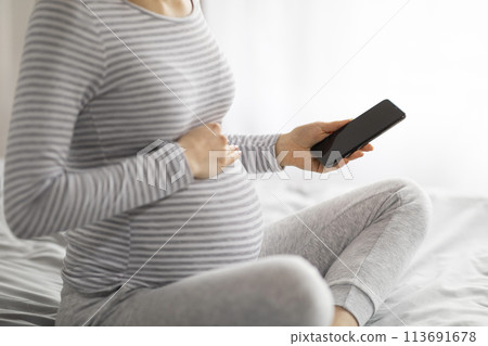 Close up of pregnant woman holding smartphone 113691678