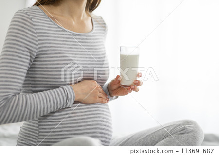 Expecting mother holding a glass of milk gently Expecting mother holding a glass of milk gently 113691687