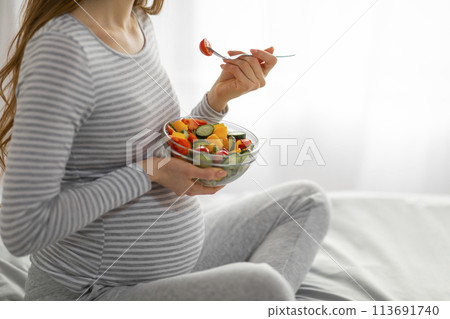 Pregnant woman enjoying a nutritious salad meal Pregnant woman enjoying a nutritious salad meal 113691740