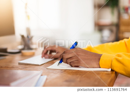 Person writing notes beside a computer Person writing notes beside a computer 113691764