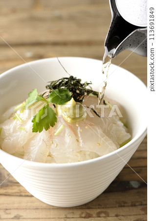 將高湯倒在配有三葉、海藻絲和芥末的鯛魚茶泡飯上。 113691849