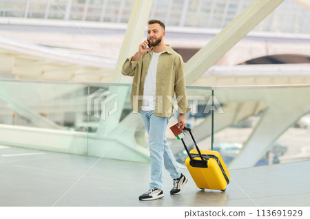 Man Walking With Luggage and Talking on Phone at Airport Man Walking With Luggage and Talking on Phone at Airport 113691929