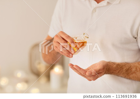 Man presenting a bottle of golden oil 113691936