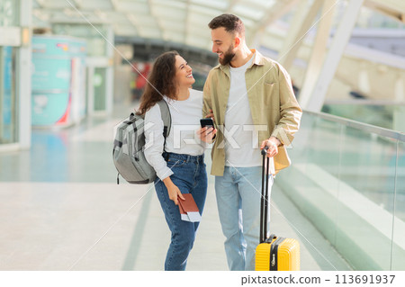 Man and Woman Walking Through Airport With Luggage 113691937