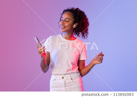 Curly-haired woman holding phone and gesturing 113692063
