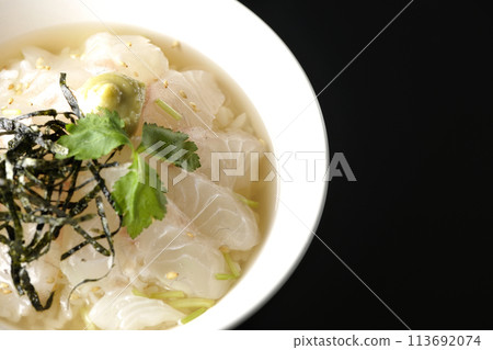 黑色背景下，頭頂上放著三葉草、海藻絲和芥末的 tai chazuke 的照片 113692074