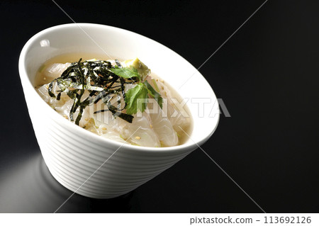 Sea bream chazuke topped with mitsuba, shredded seaweed, and wasabi photographed against a black background Sea bream chazuke topped with mitsuba, shredded seaweed, and wasabi photographed against a black background 113692126