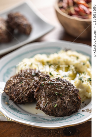 Minced meat cutlets with mashed potatoes topped with clarified butter. Traditional Slovak meatballs - Fasirky with potato puree. 113692696