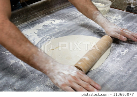 Dough with motion hands with rolling pin on wooden table Dough with motion hands with rolling pin on wooden table 113693077