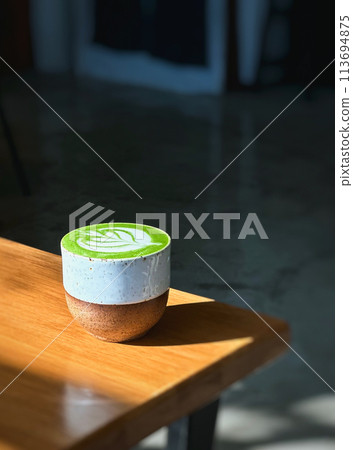 Cup of matcha latte green tea on wooden table. 113694875