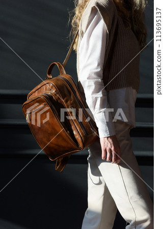 beautiful curly blond hair woman posing with a leather backpack beautiful curly blond hair woman posing with a leather backpack 113695137